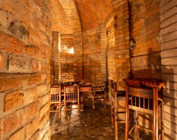 Una habitación rústica con paredes de ladrillo visto, suelo de piedra, muebles de madera y techo de ladrillo.