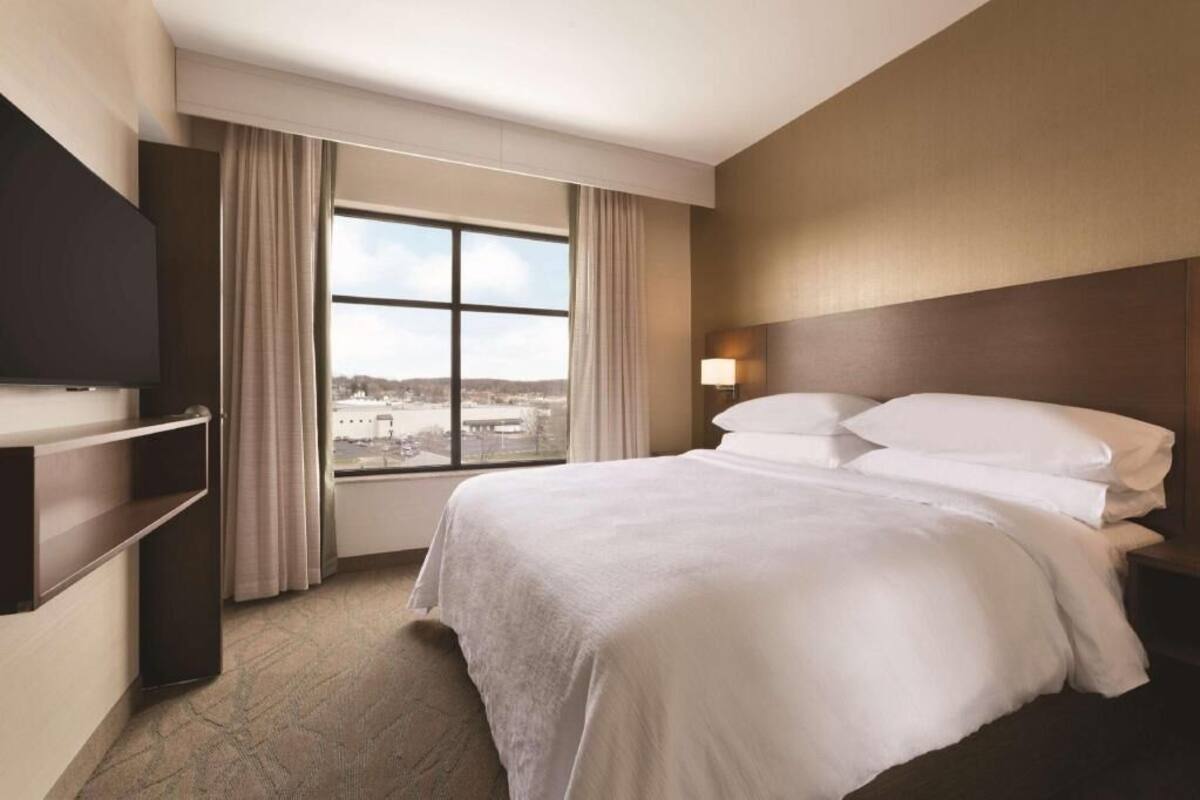 Une chambre d’hôtel avec un grand lit, une télévision, une fenêtre avec des rideaux et une vue sur la ville.