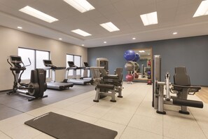 Un gimnasio con cintas de correr, elípticas, máquinas de pesas y pelotas de ejercicio.