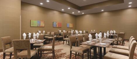 A conference room with multiple tables and chairs, equipped with white tablecloths and glassware.