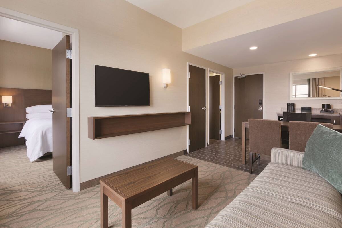 Une chambre d’hôtel comprenant un lit, une télévision, un bureau avec des chaises et un canapé.