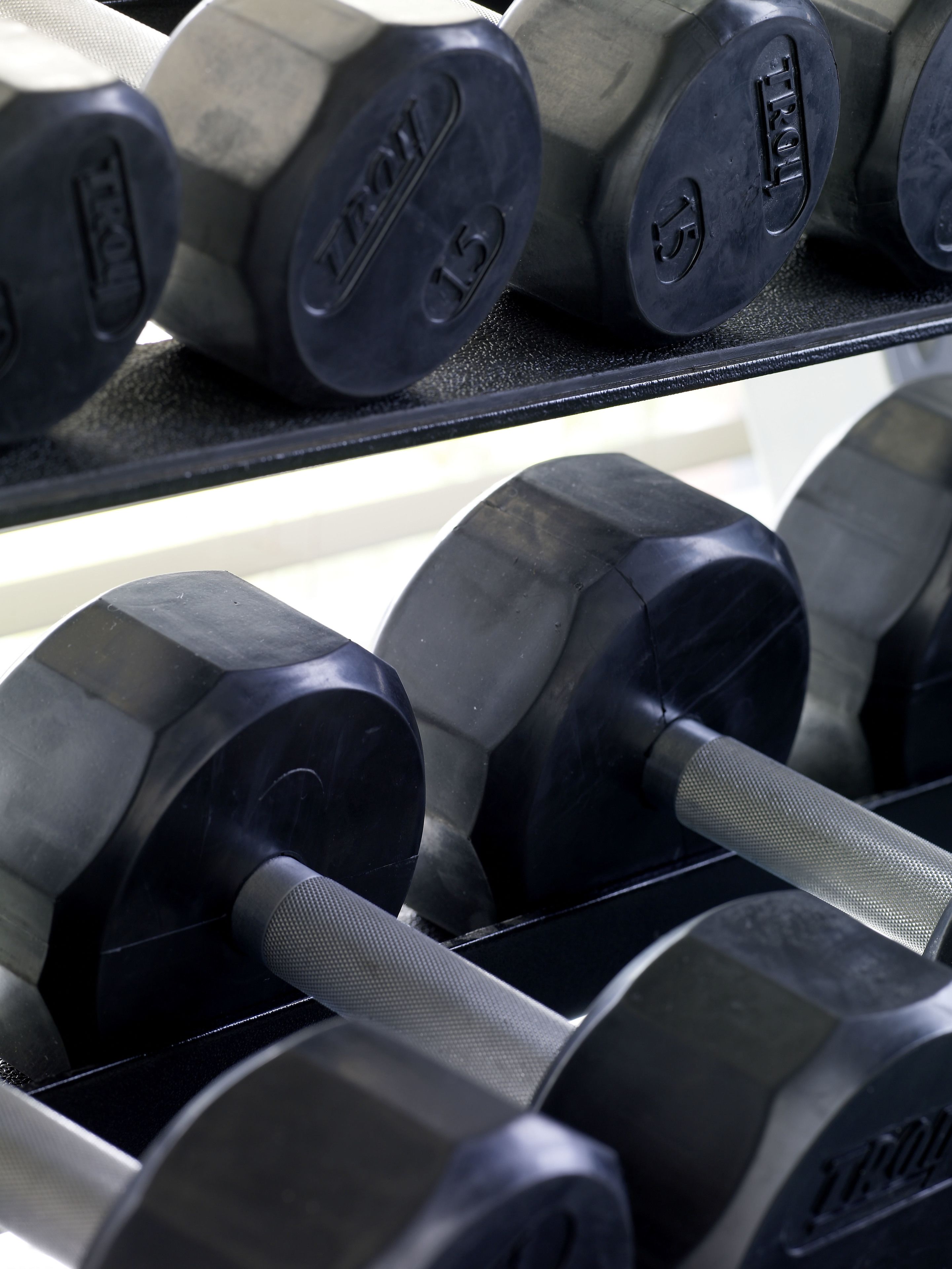 A rack of weightlifting dumbbells with visible weight markings.
