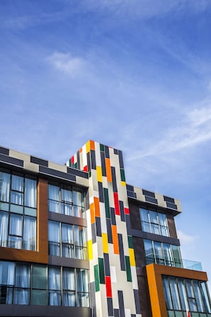 Contemporary building with a geometric facade, featuring clean lines and multiple windows with curtains.