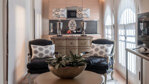 A modern living room with a round coffee table, two armchairs, and a kitchen in the background.