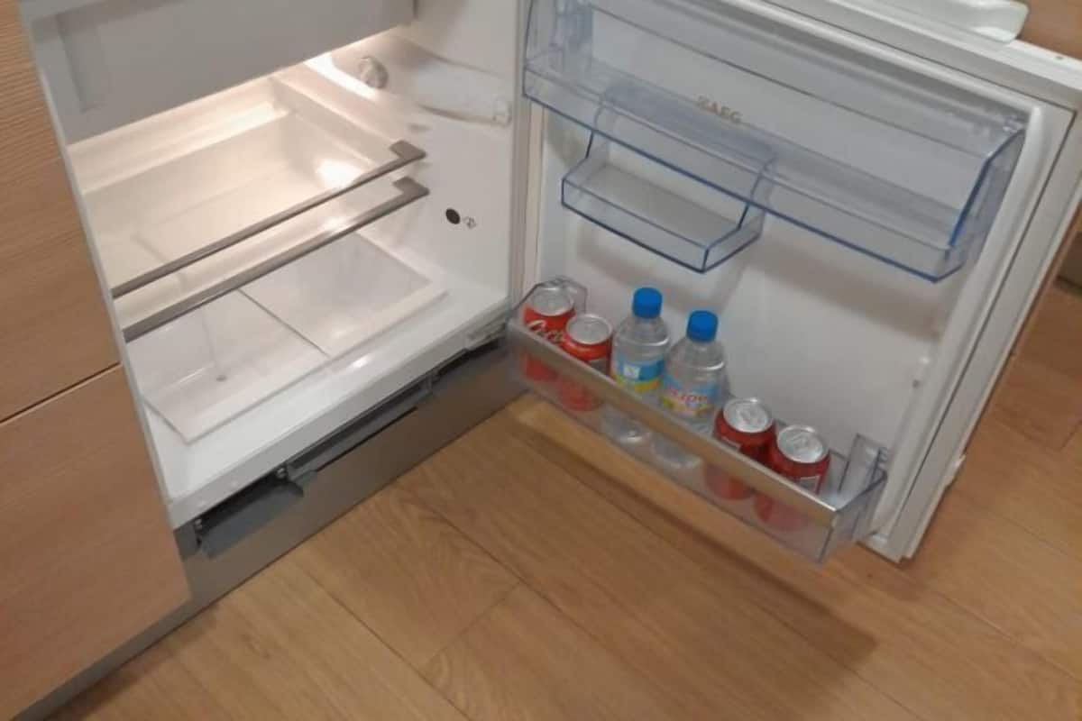 An open refrigerator with clear shelves, a freezer compartment, and a water dispenser.