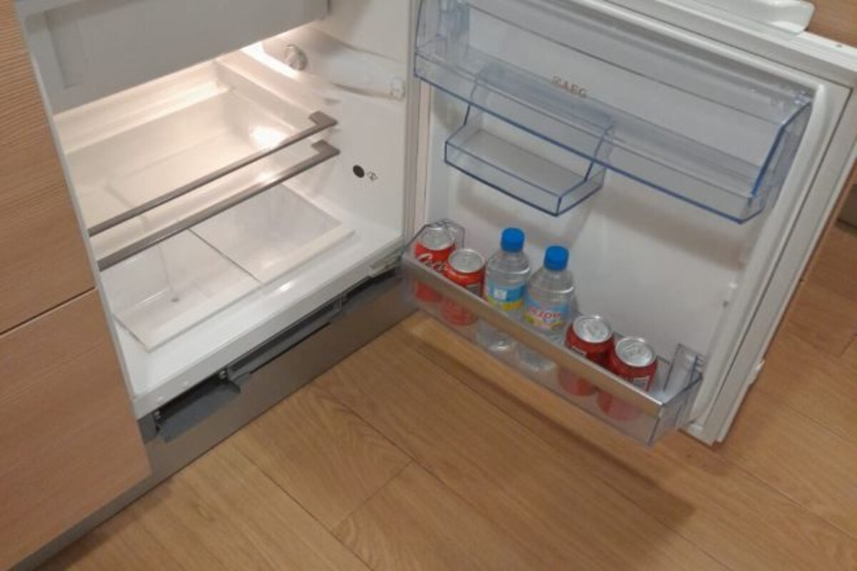 An open refrigerator with clear shelves, a freezer compartment, and a water dispenser.