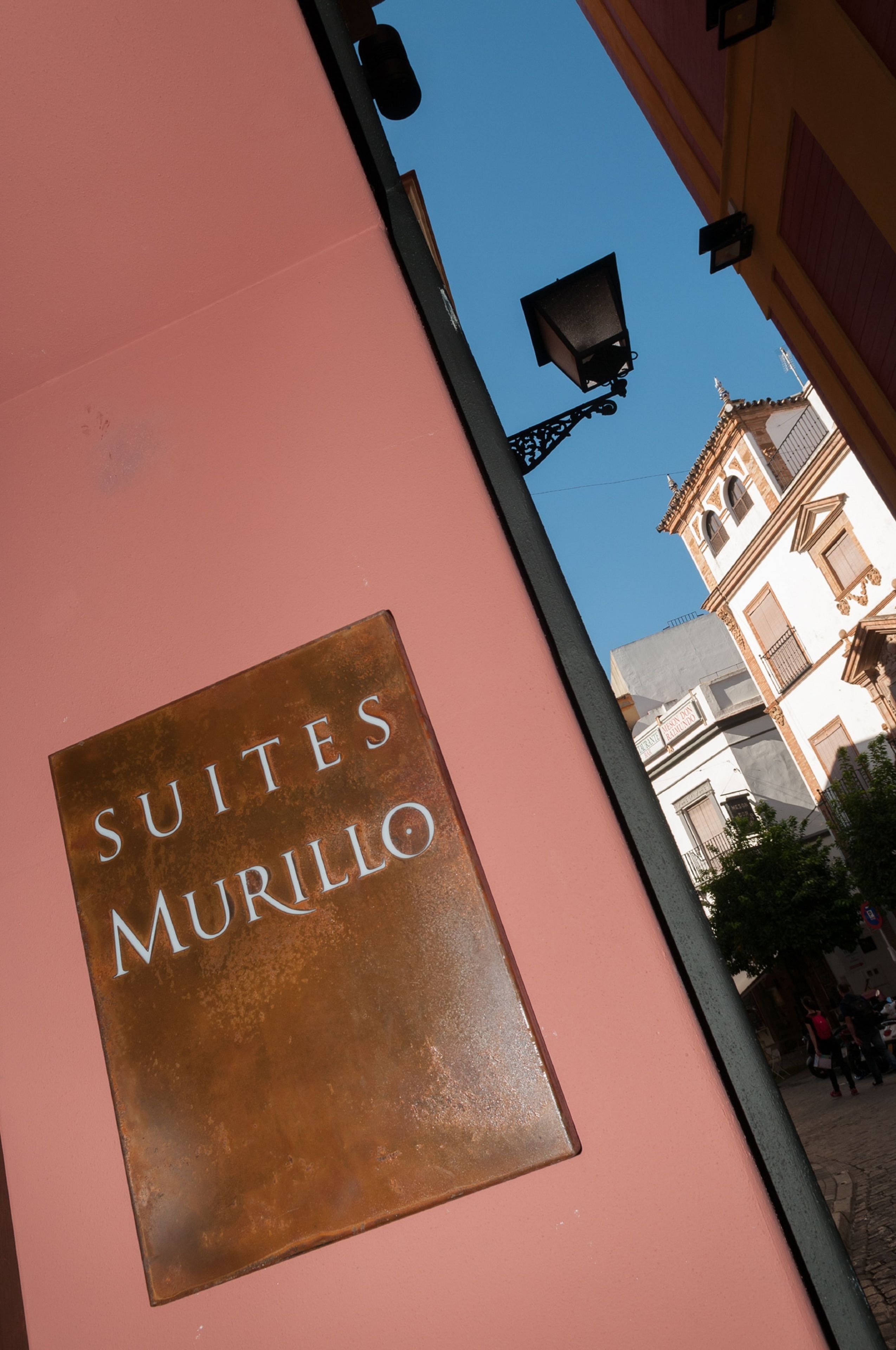A sign for 'Suites Murillo' on a pink wall.