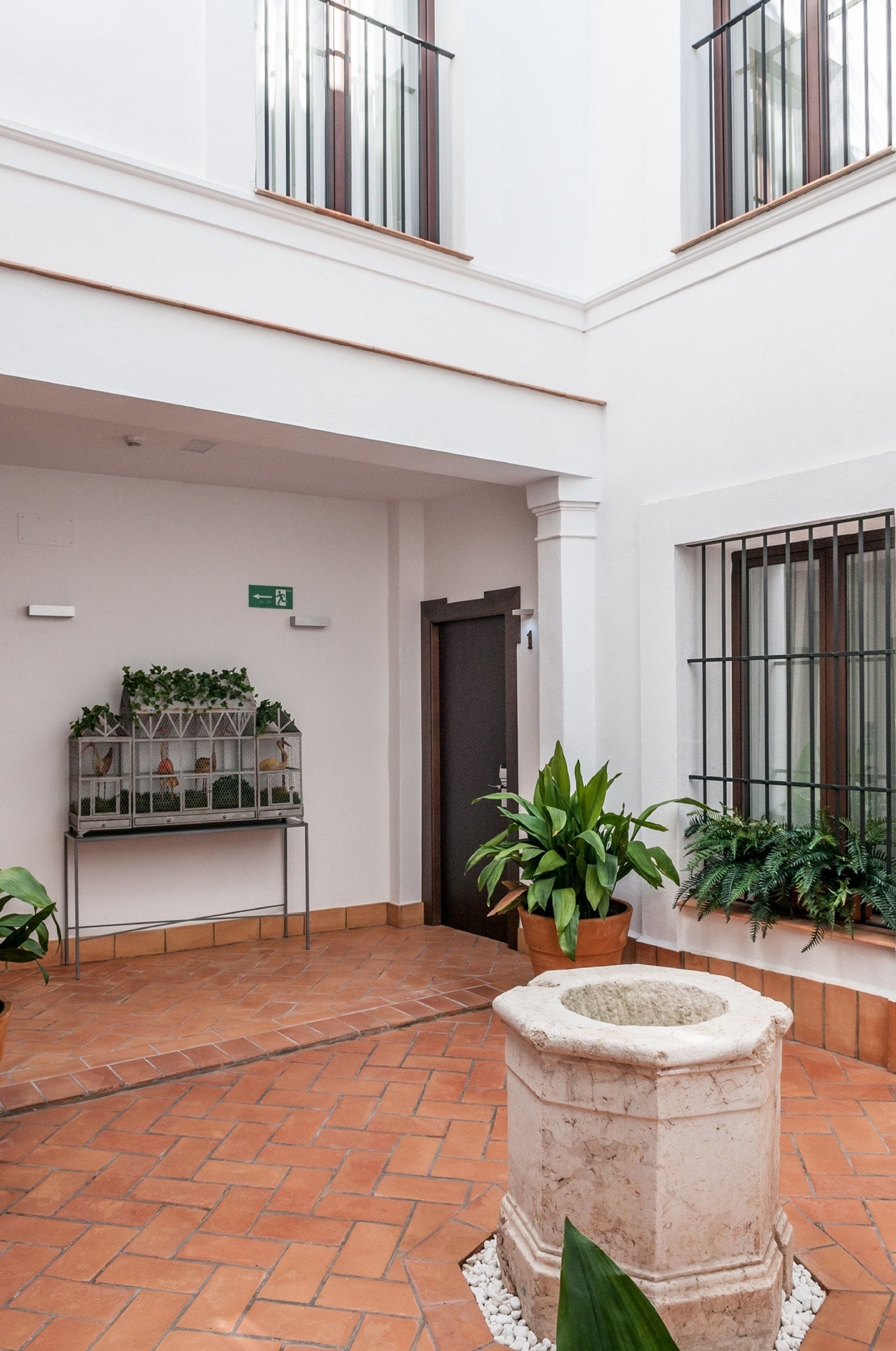 A courtyard with a tiled floor, a stone planter, and potted plants.