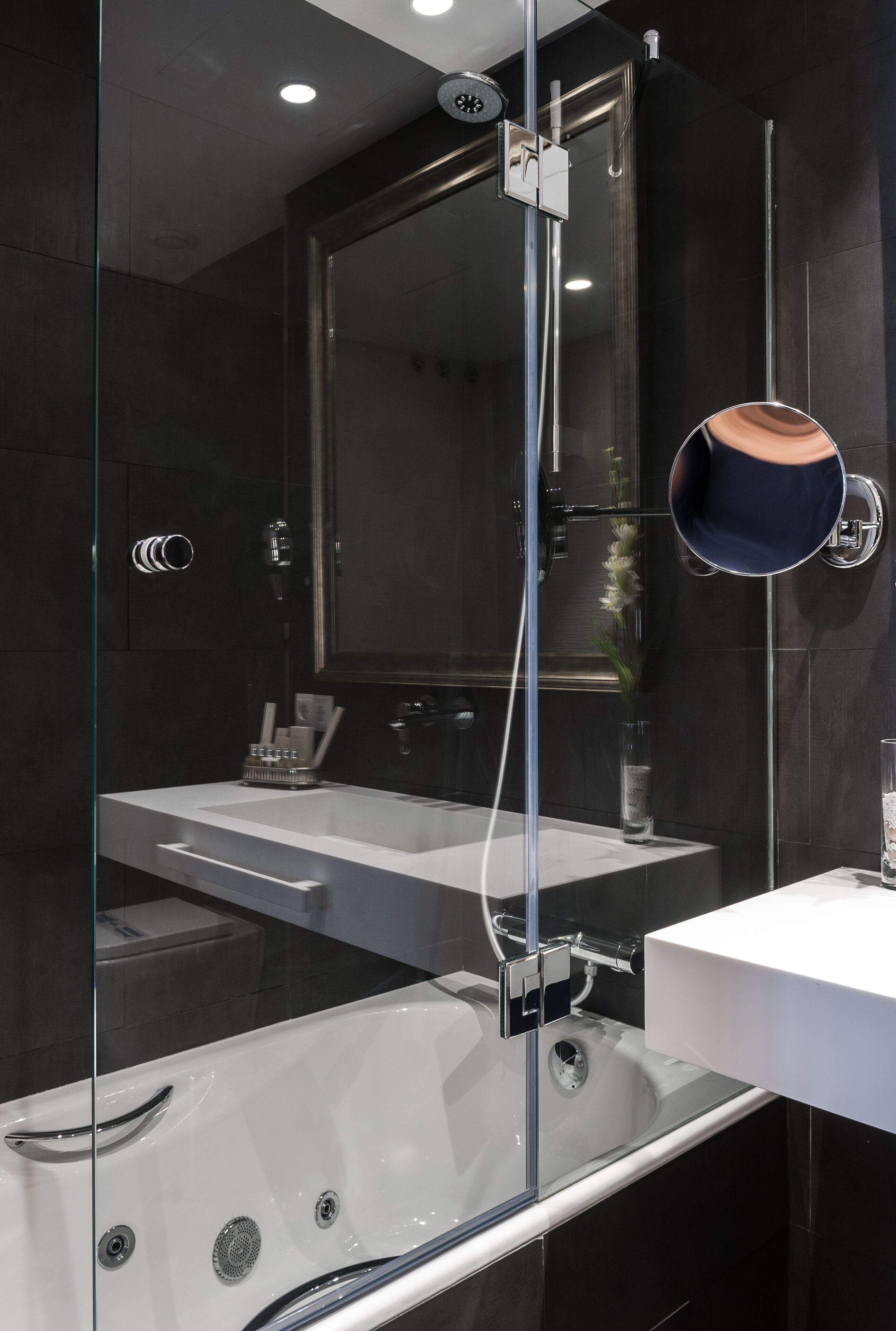 A modern bathroom with a glass-enclosed shower, a white sink, and a large mirror.