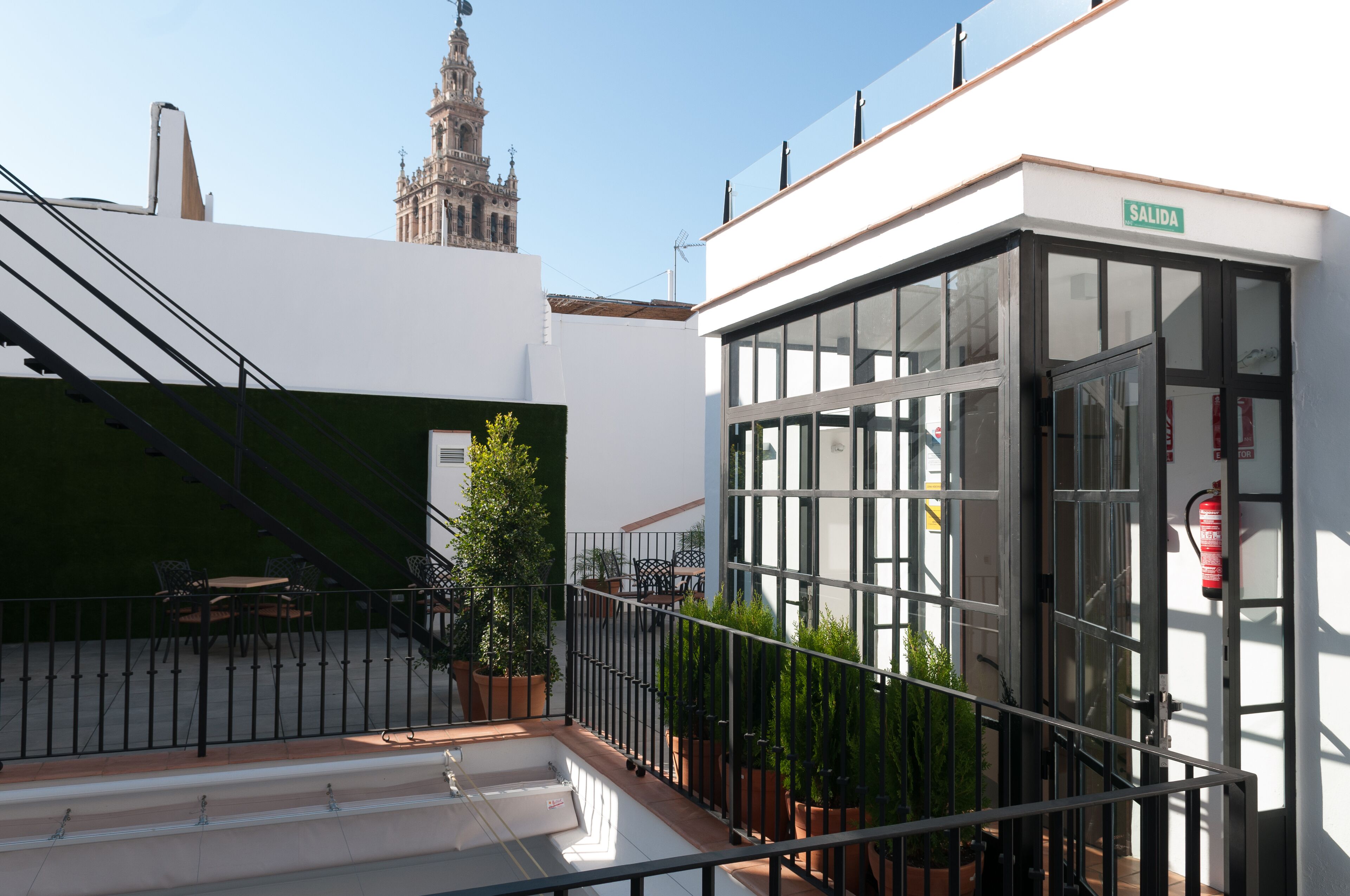 Un edificio moderno con fachada de vidrio, un cartel que dice "SALIDA" y una vista de una torre histórica al fondo.