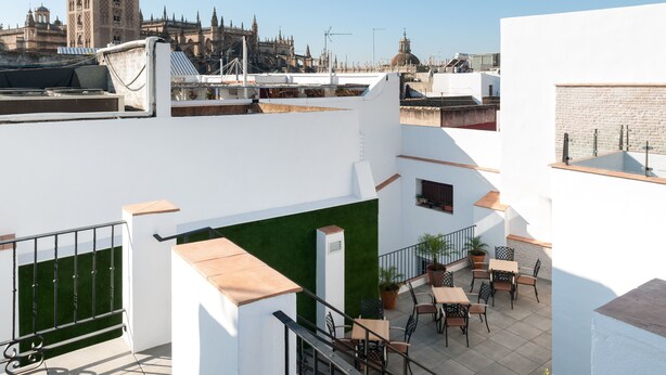 A rooftop terrace with outdoor seating, a view of historic architecture, and a clear sky.