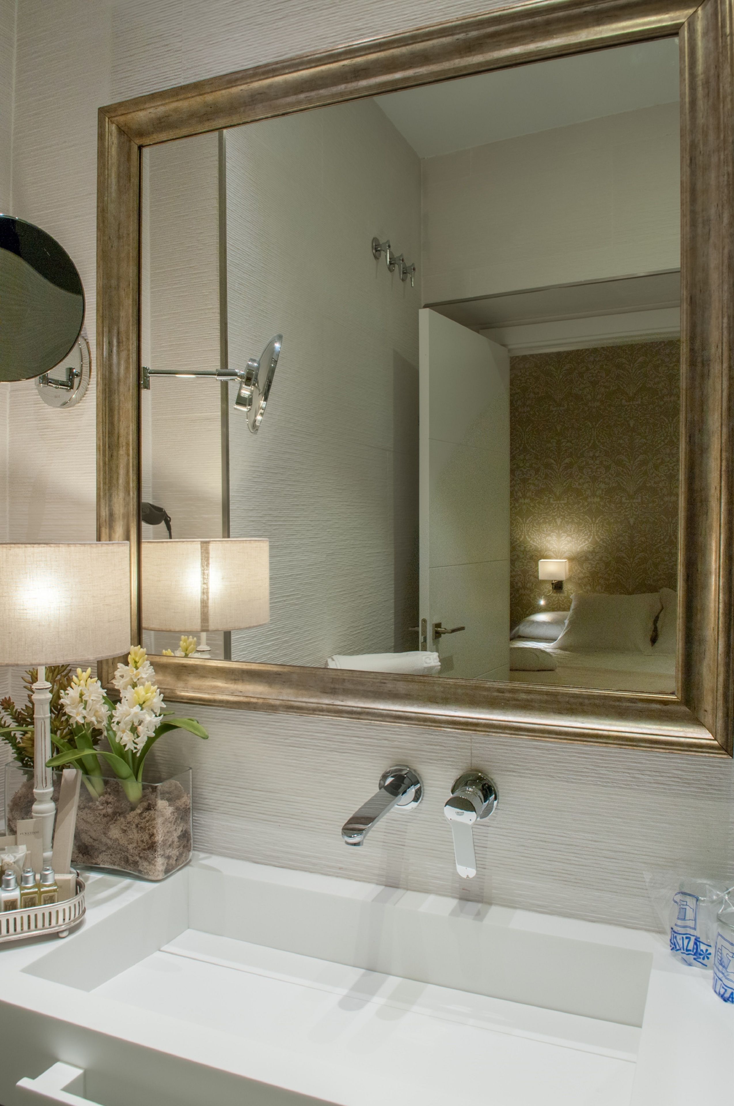 A bathroom with a large mirror, a sink, and a shower.