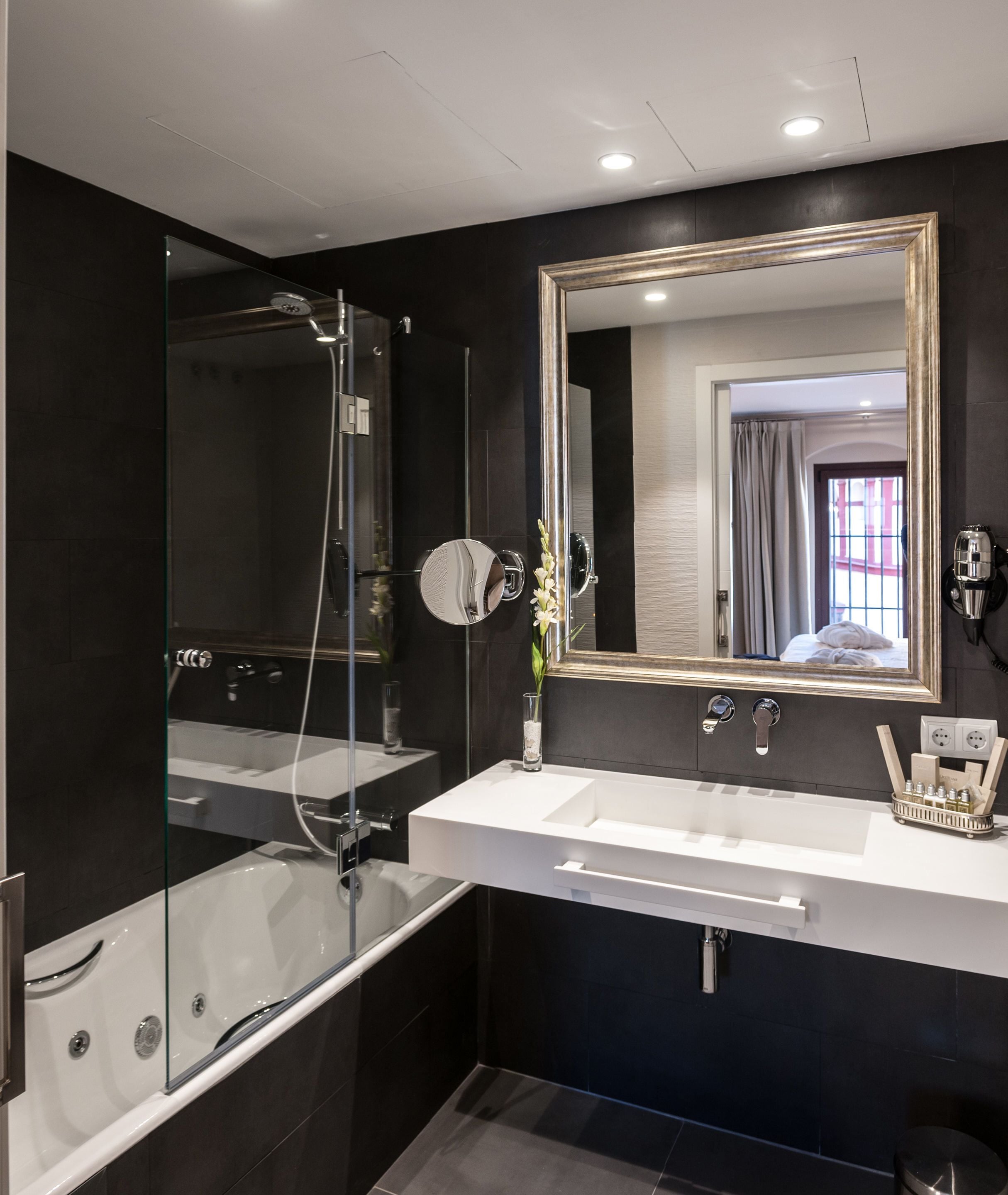 A modern bathroom with a glass-enclosed shower, a large mirror, and a white sink.