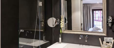 A modern bathroom with a glass-enclosed shower, a large mirror, and a white sink.