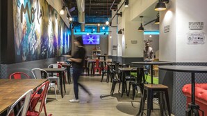 A restaurant interior with tables, chairs, and a mural on the wall. - Mola Hostel (Madrid)