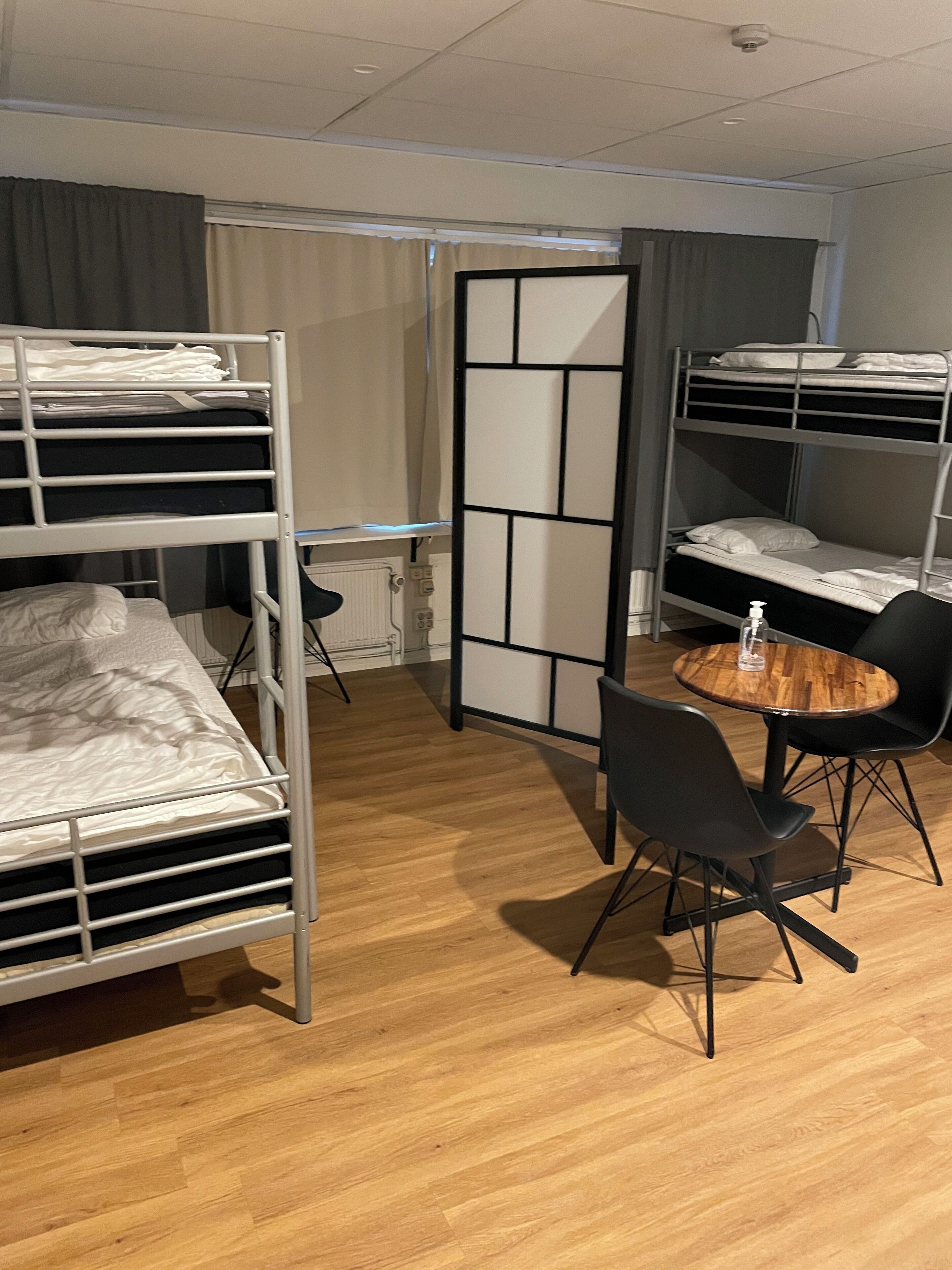 A room with bunk beds, a round wooden table, and black chairs.