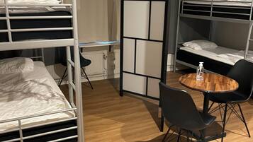 A room with bunk beds, a round wooden table, and black chairs.