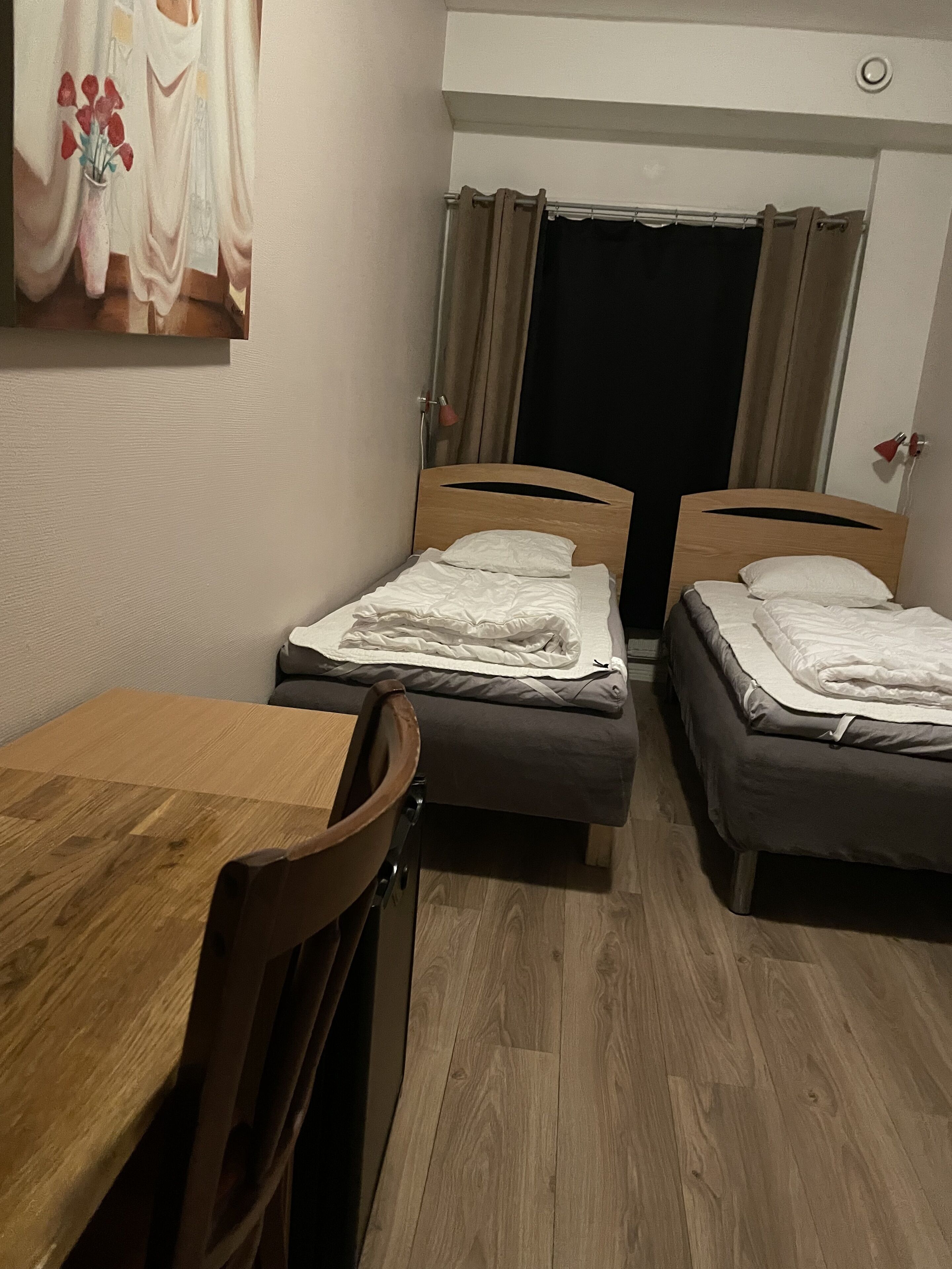 A room with two single beds, a wooden table, and a chair.