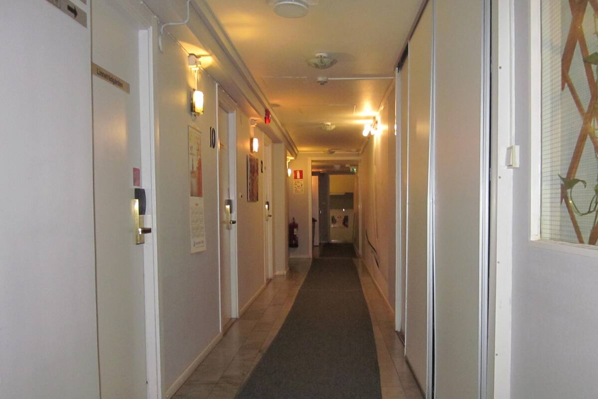 Pasillo de hotel con puertas, luminarias y un extintor.