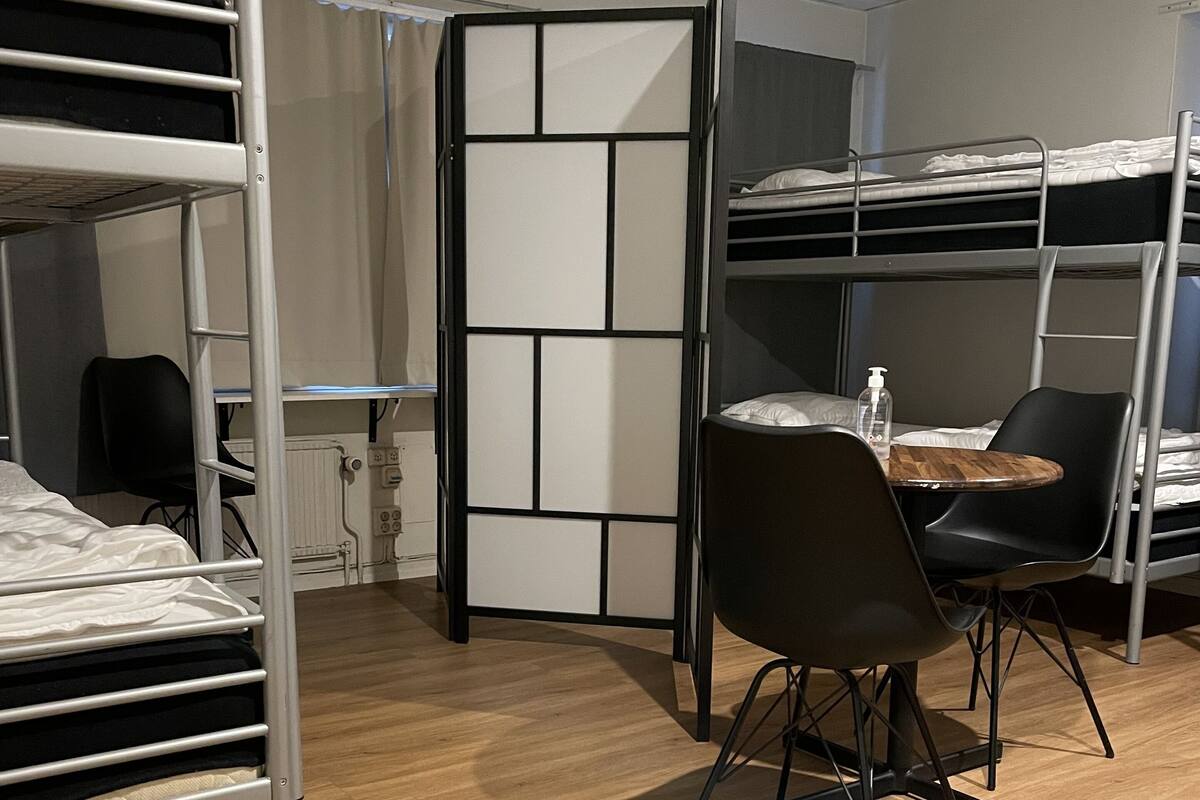 Una habitación con literas, un escritorio, una silla y un separador con un diseño geométrico.