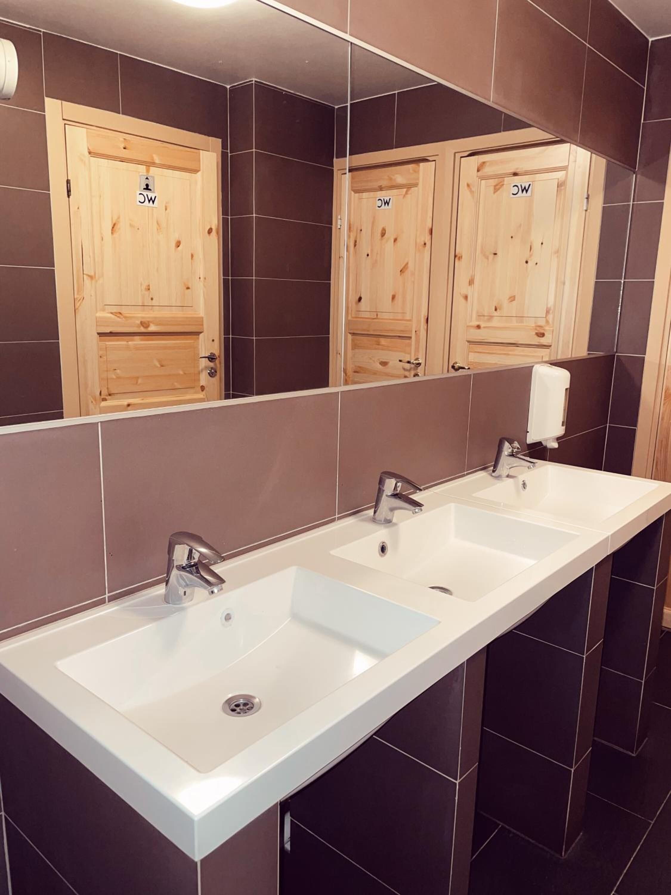 Un baño moderno con tres lavamanos, armarios de madera y un espejo grande.