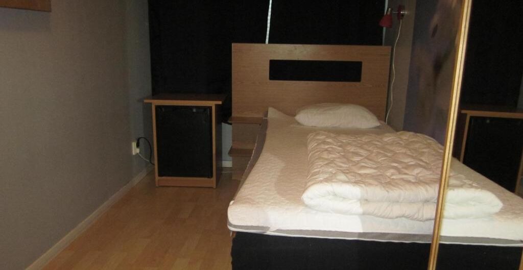 A single bed with a wooden headboard, a bedside table, and a bedside lamp.