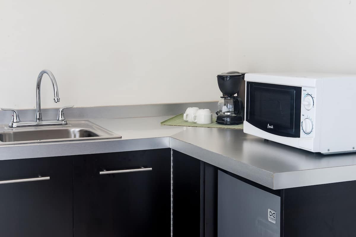 A kitchen with a stainless steel sink, a coffee maker, and a microwave.
