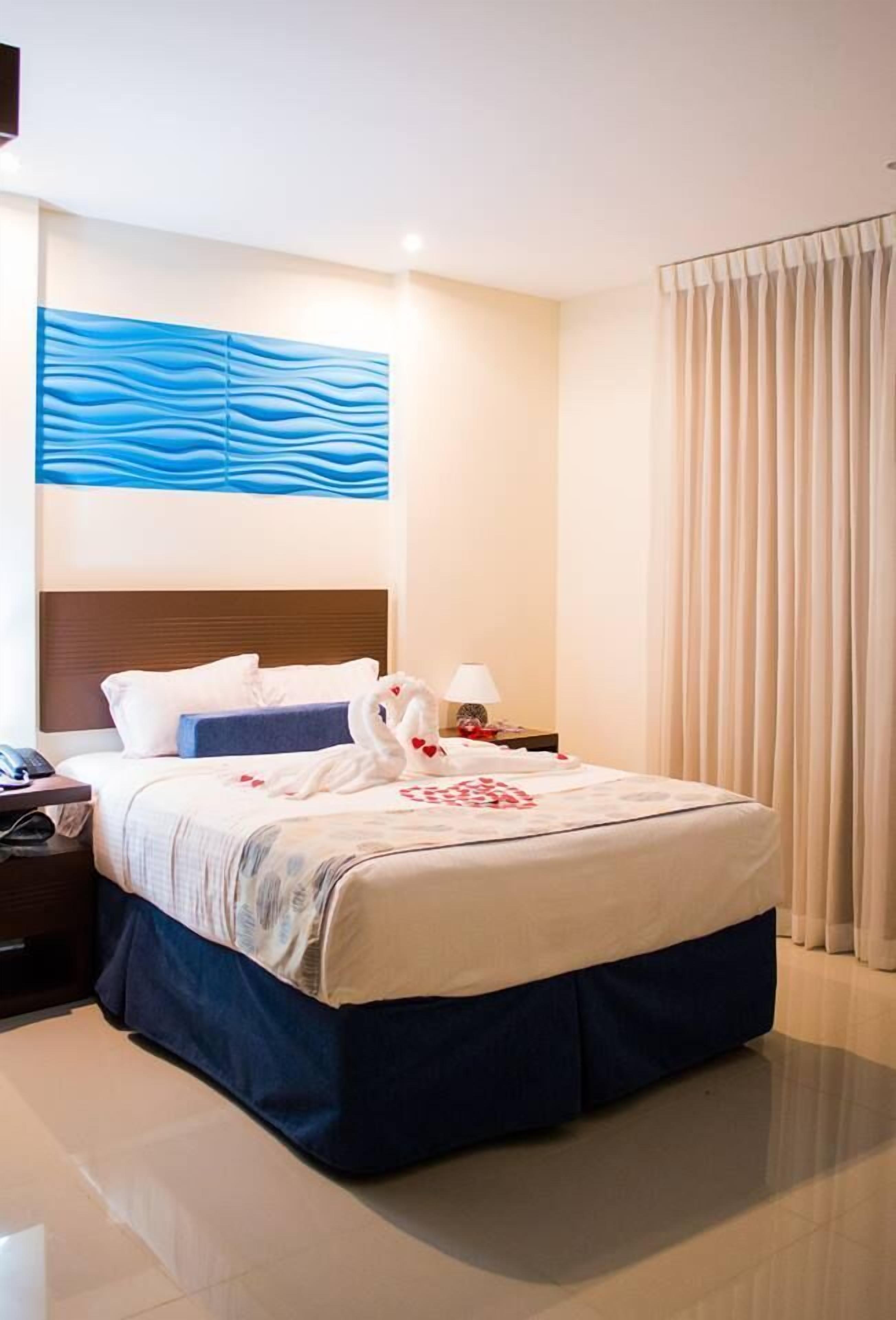 Habitación de hotel con una cama grande, una mesita de noche, una lámpara y una obra de arte colgada en la pared.