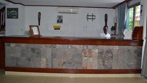 A reception desk with a stone-tiled front, a framed certificate, and a portrait on the wall. - Hôtel Lumière D'Akwa (Douala)