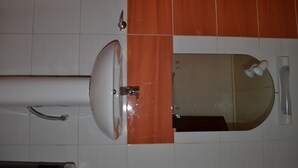 A bathroom with a sink, mirror, and orange-tiled wall. - Hôtel Lumière D'Akwa (Douala)
