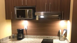 A kitchen with dark wooden cabinets, a stainless steel microwave, a coffee maker, and a built-in oven. - Las 7 Maravillas - Adults Only (Mazatlán)