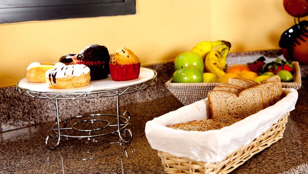 Ein Frühstücksbuffet mit Gebäck, Brot und Obst auf einer Küchenarbeitsplatte.