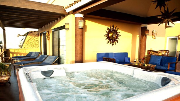 A hot tub in a sunlit room with a wooden ceiling, a sofa, and a decorative wall piece. - Las 7 Maravillas - Adults Only (Mazatlán)