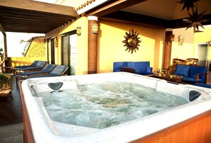 Un jacuzzi en una habitación iluminada por el sol, con techo de madera, un sofá y un adorno en la pared.