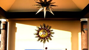 A room with a star-shaped hanging light fixture, a sunburst wall decoration, blue upholstered seating, and a tiled floor. - Las 7 Maravillas - Adults Only (Mazatlán)