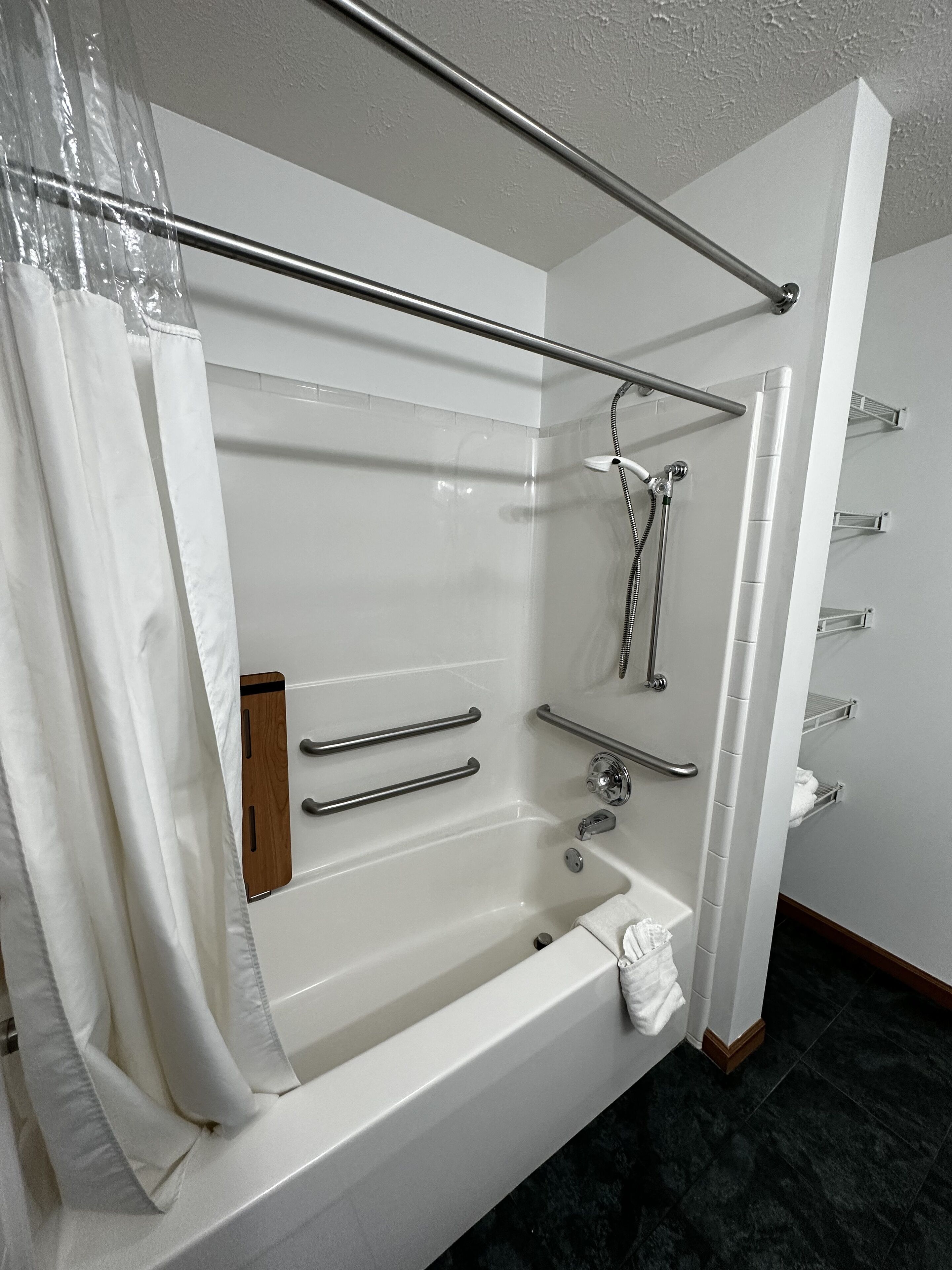 Un baño moderno con bañera, ducha y barras de apoyo.