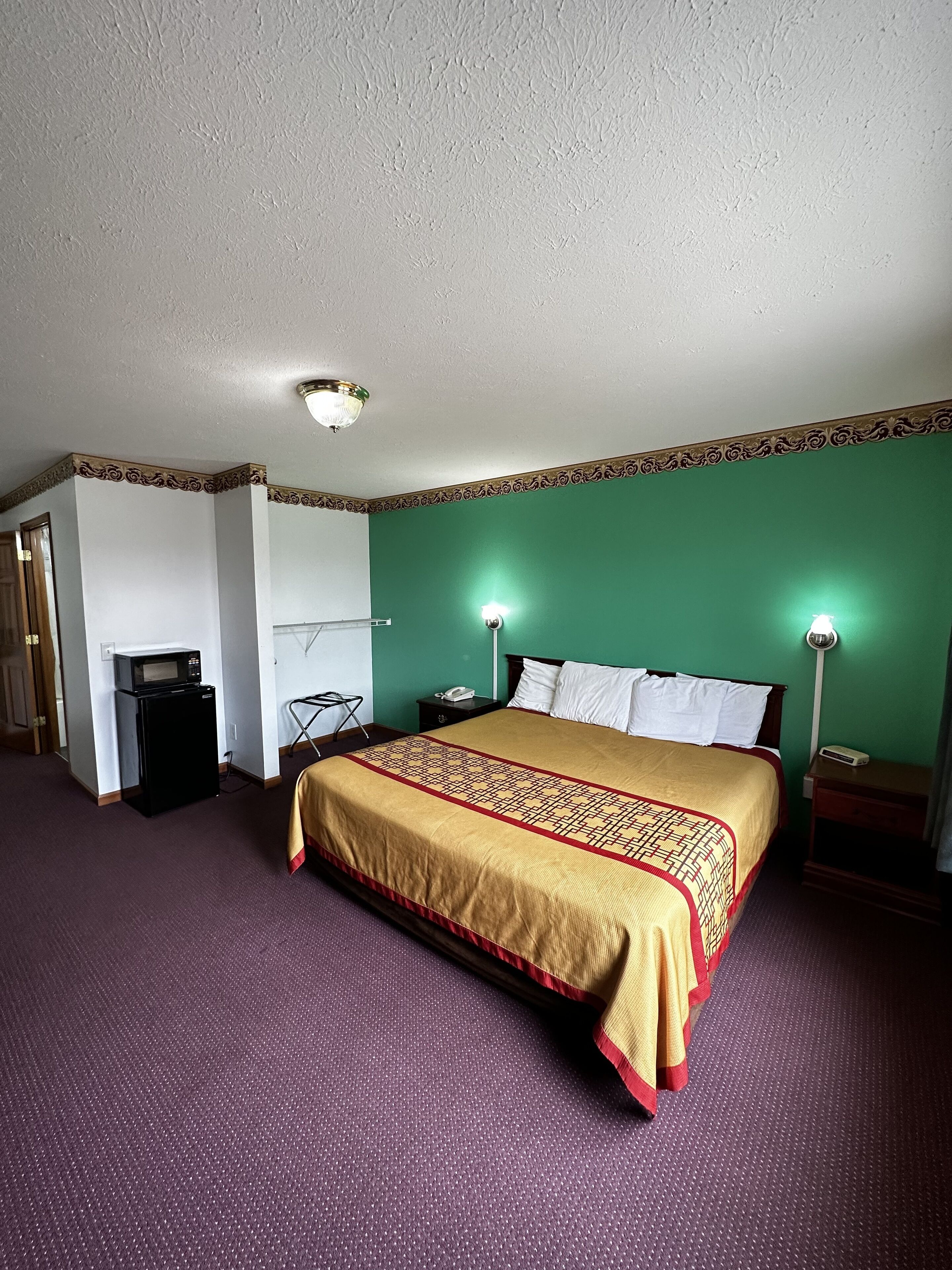 Une chambre d’hôtel équipée d’un grand lit, d’un bureau, d’une chaise, d’un four à micro-ondes et d’un téléphone.