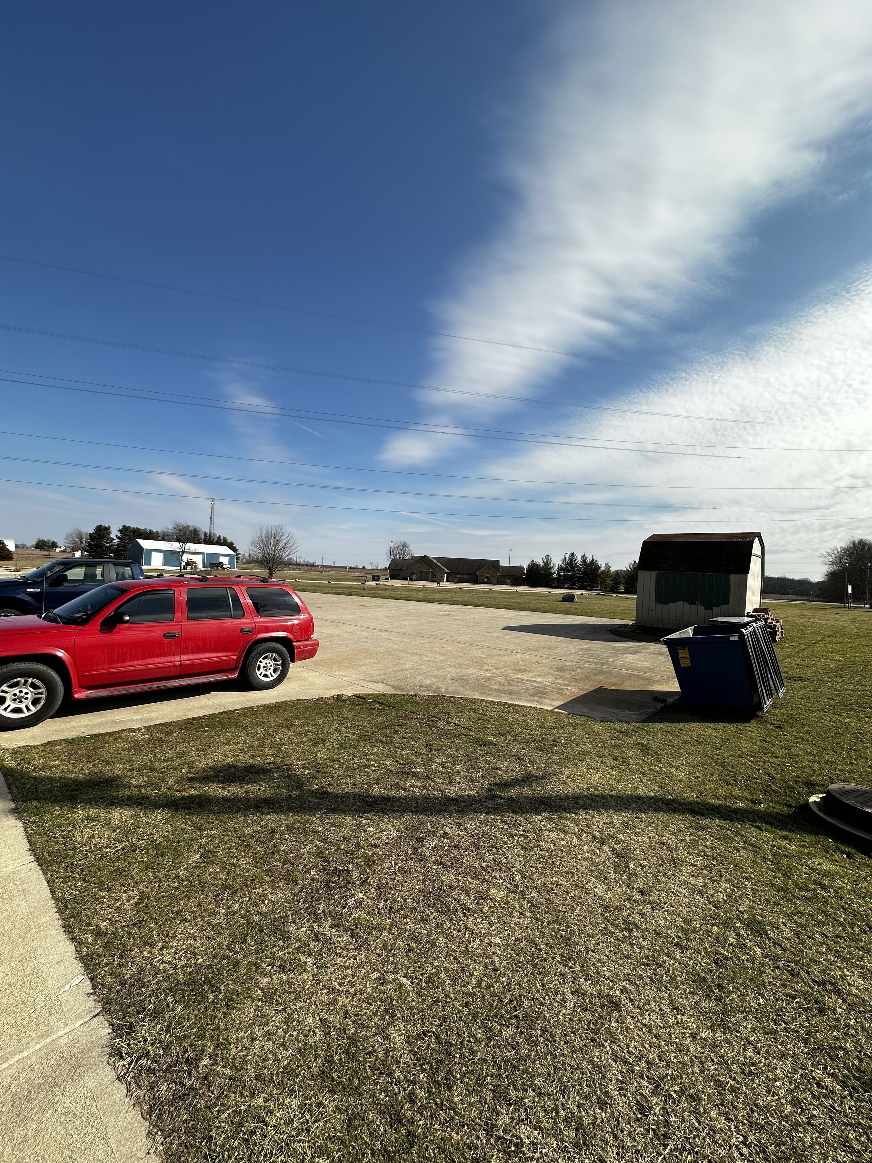 A parking lot with a red car and a white trailer.