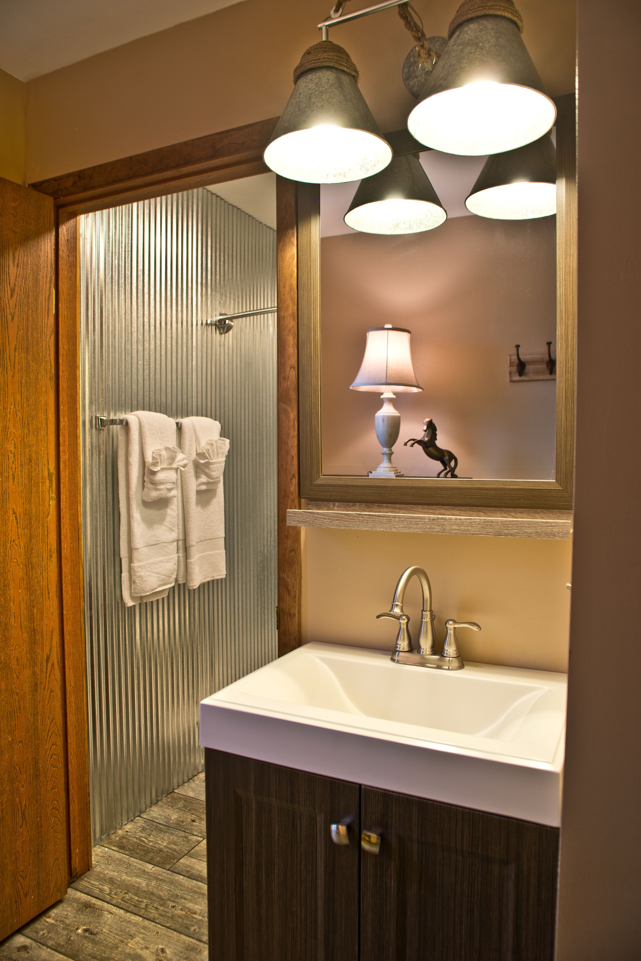 A bathroom with a wooden door, a white sink, and a mirror above it.
