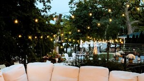 A cozy outdoor seating area with a fire pit and string lights. - Maxwell Mansion (Lake Geneva)