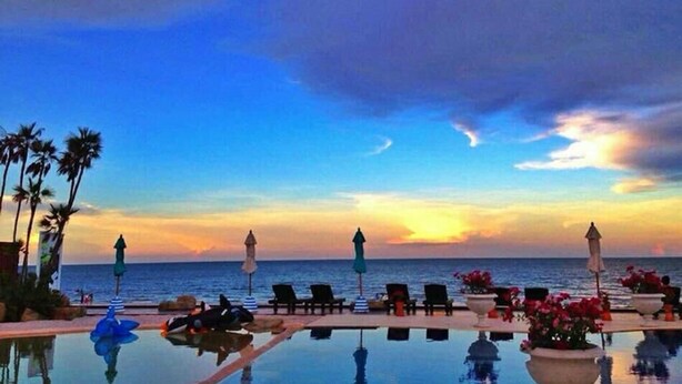 A poolside area with lounge chairs and umbrellas, overlooking the ocean at sunset. - My Resort HuaHin E503 (Hua Hin)