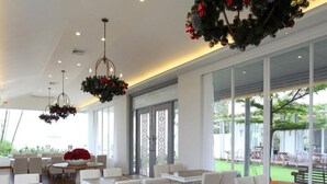 A spacious indoor dining area with white furniture, large windows, and decorative hanging lights. - My Resort HuaHin E503 (Hua Hin)