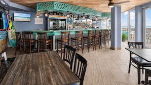 Un restaurant doté d’un bar, d’un plafond en bois et offrant une vue sur l’océan.