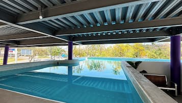 Una piscina al aire libre, sillones reclinables de piscina