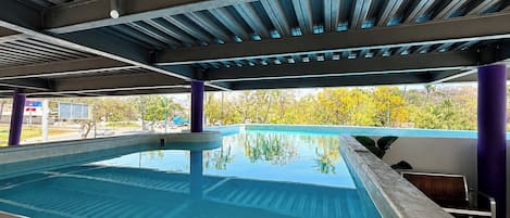 Una piscina al aire libre, sillones reclinables de piscina