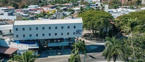 A hotel with a flat roof, multiple floors, and a parking lot.