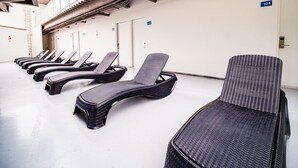 Una fila de sillones de mimbre en un espacio interior limpio y bien iluminado, con techo alto y conductos visibles.
