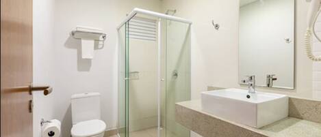 A modern bathroom with a glass shower enclosure, a white sink, and a toilet.
