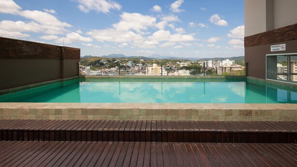 A rooftop pool with a clear view of a cityscape and mountains in the background. - Tri Hotel Executive Brusque (Brusque)