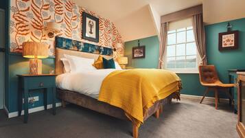 A bedroom with a bed, a nightstand, a chair, a window with a view, and a wall with patterned wallpaper.